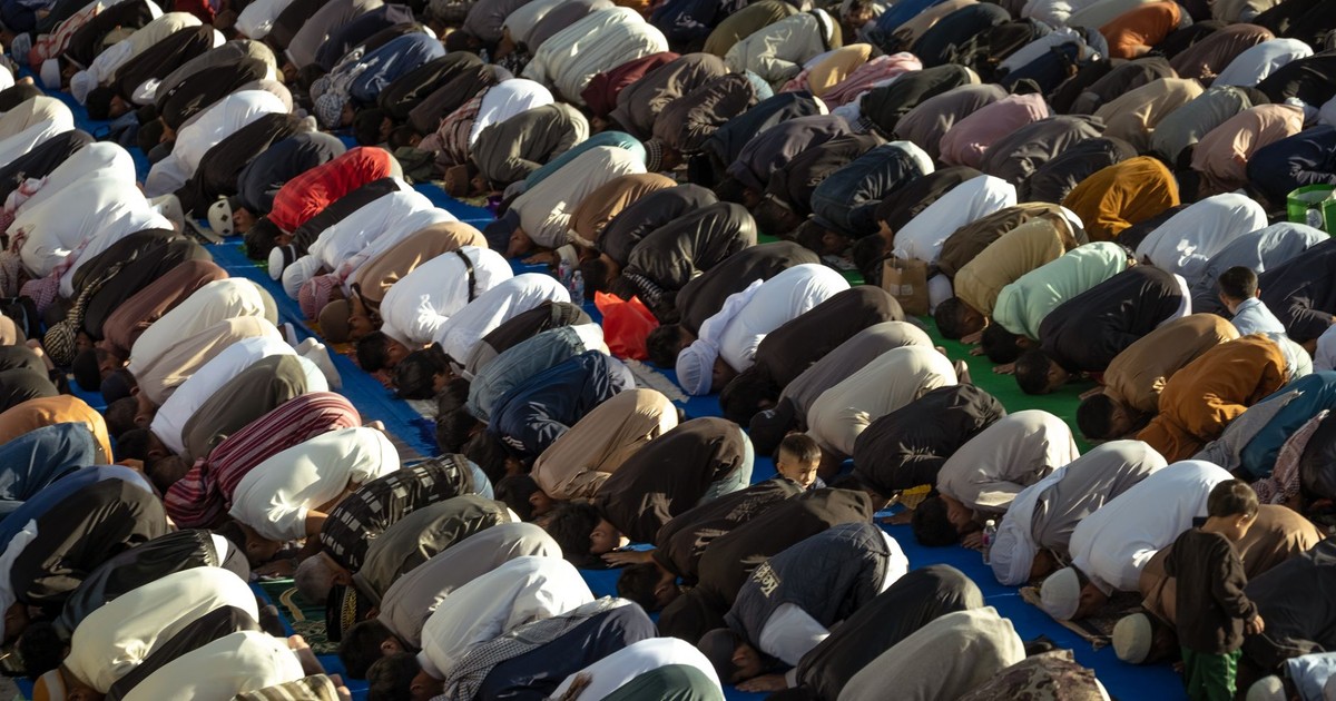 An outdoor gathering of people in prayer, symbolizing communal worship and religious devotion.