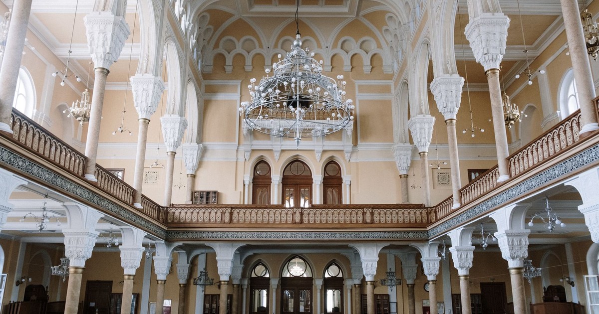 Captivating view of a historic synagogue interior with ornate architecture, chandeliers, and arches.