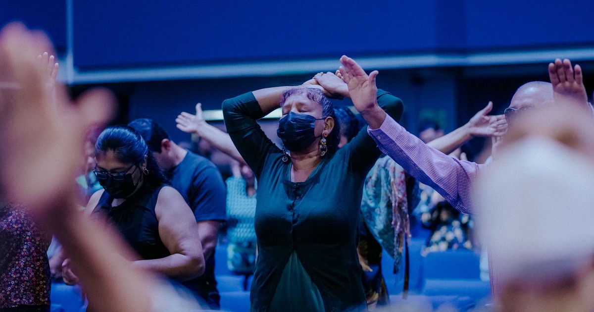 A group of people wearing masks, praying in a church setting, highlighting spirituality and safety.