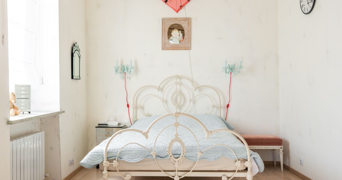 Charming vintage bedroom decor with an antique iron bed and pastel tones, perfect for cozy interiors.