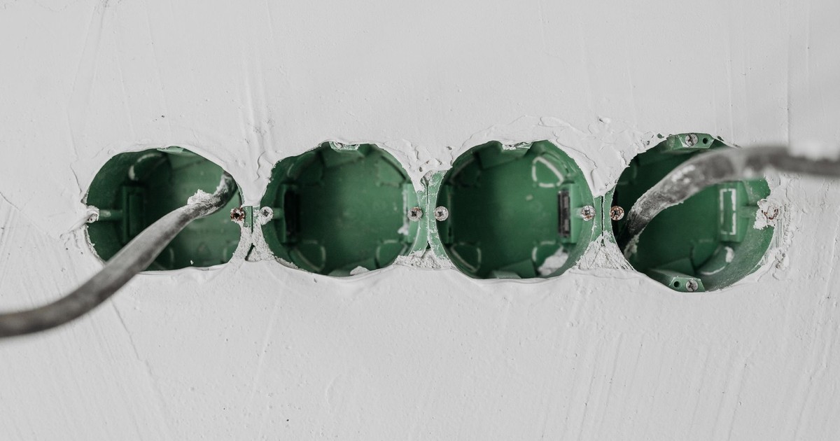 Close-up of green electrical boxes and wiring in a wall setup.
