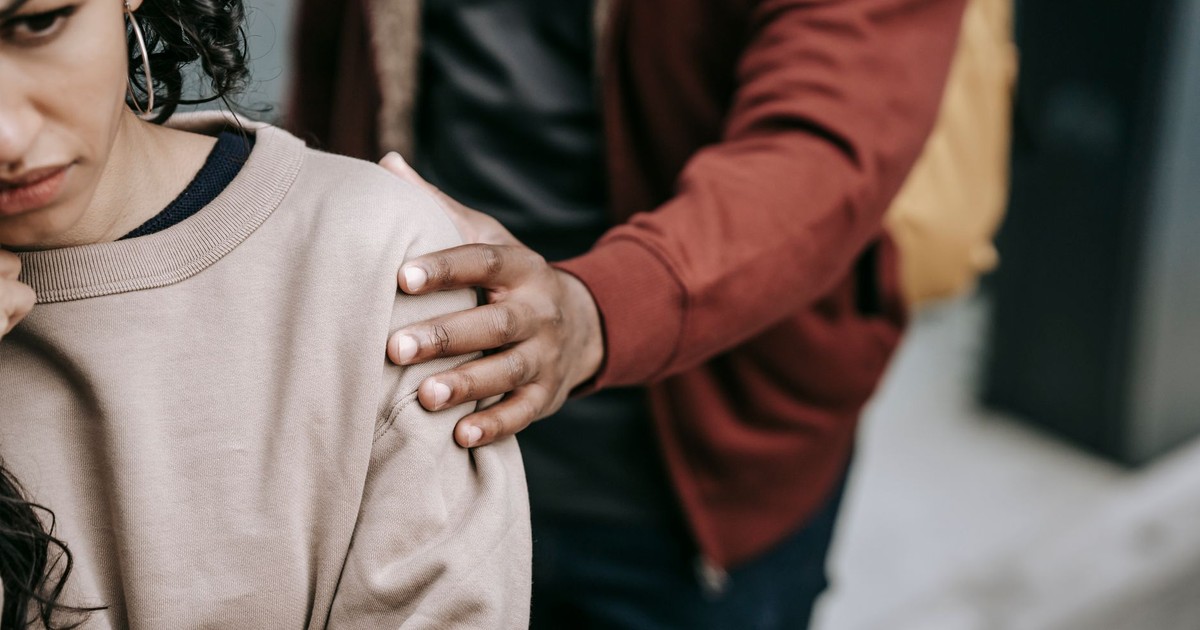 Crop unrecognizable unhappy young multiracial couple in casual outfit standing in city street while having conflict in daylight
