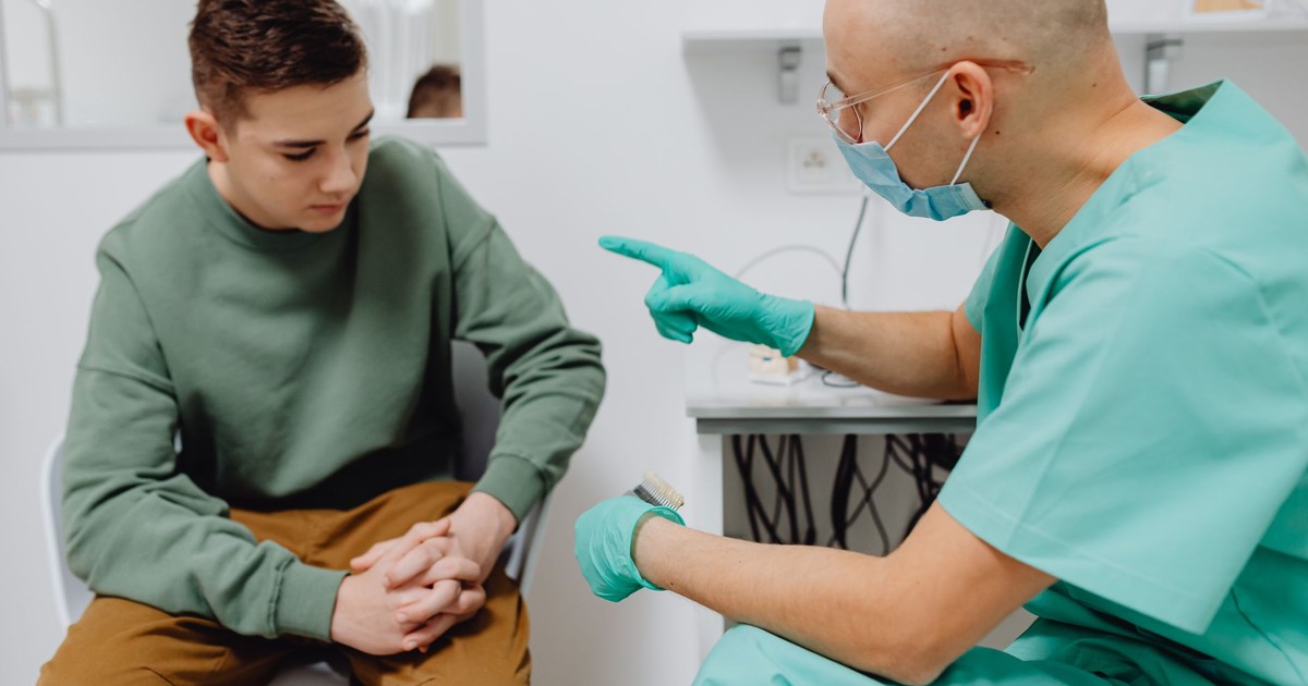 A teenager consults a doctor in a clinic, discussing health concerns.
