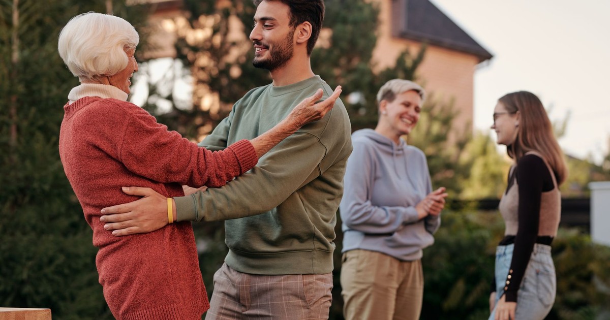 A joyful family gathering outdoors with diverse generations embracing and smiling.