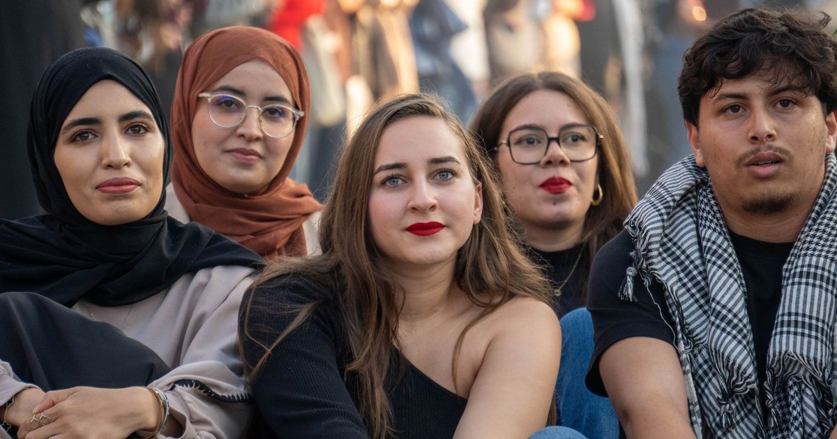 A diverse group of young adults sitting at an outdoor gathering, showcasing cultural diversity and friendship.