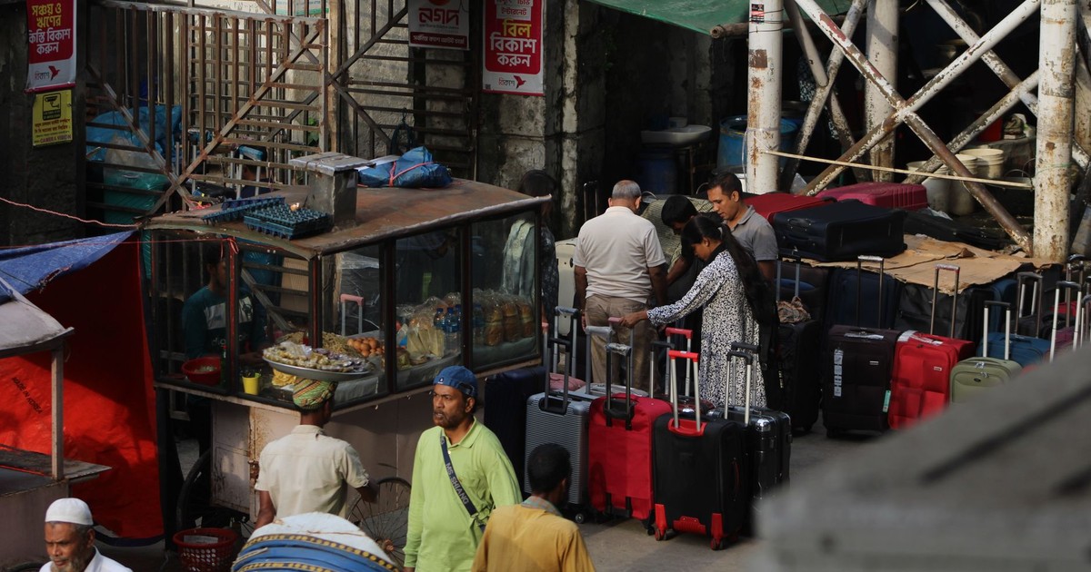 Travelers with luggage at a bustling outdoor market scene.