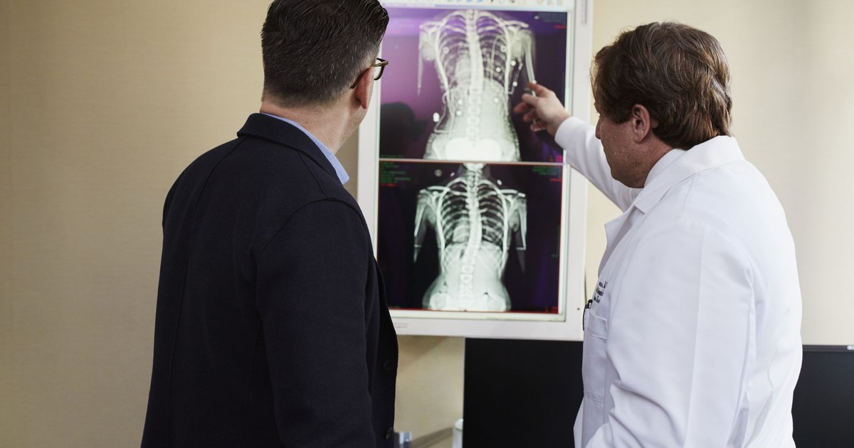 A doctor explains X-ray results to a patient in a clinical setting, highlighting healthcare communication.