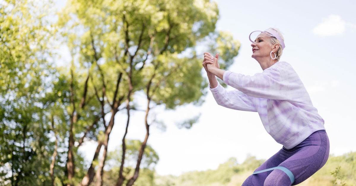 A senior woman exercises in a park with a resistance band, embracing a healthy lifestyle.