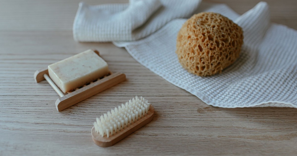 Minimalist flat lay of soap, brush, and sponge on towels, perfect for a serene bath scene.