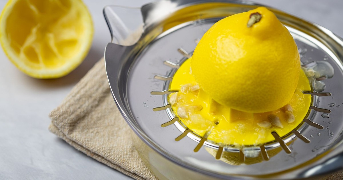 Close-up of a lemon being juiced on a metal citrus juicer, emphasizing freshness and health.