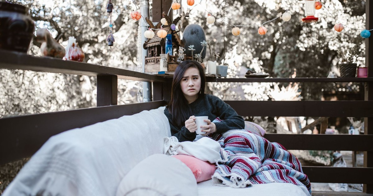 Woman enjoying a quiet afternoon with tea on a patio, wrapped in a colorful blanket.