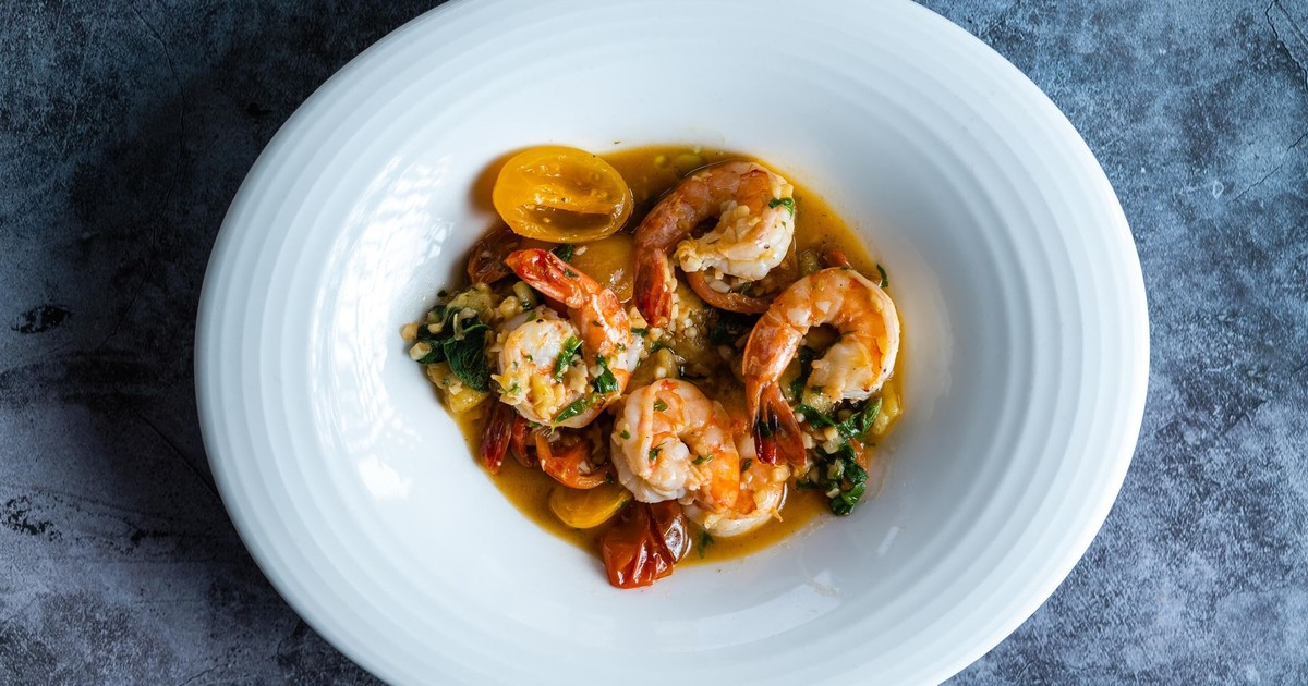 A delectable gourmet shrimp dish garnished with cherry tomatoes and fresh herbs, elegantly plated.