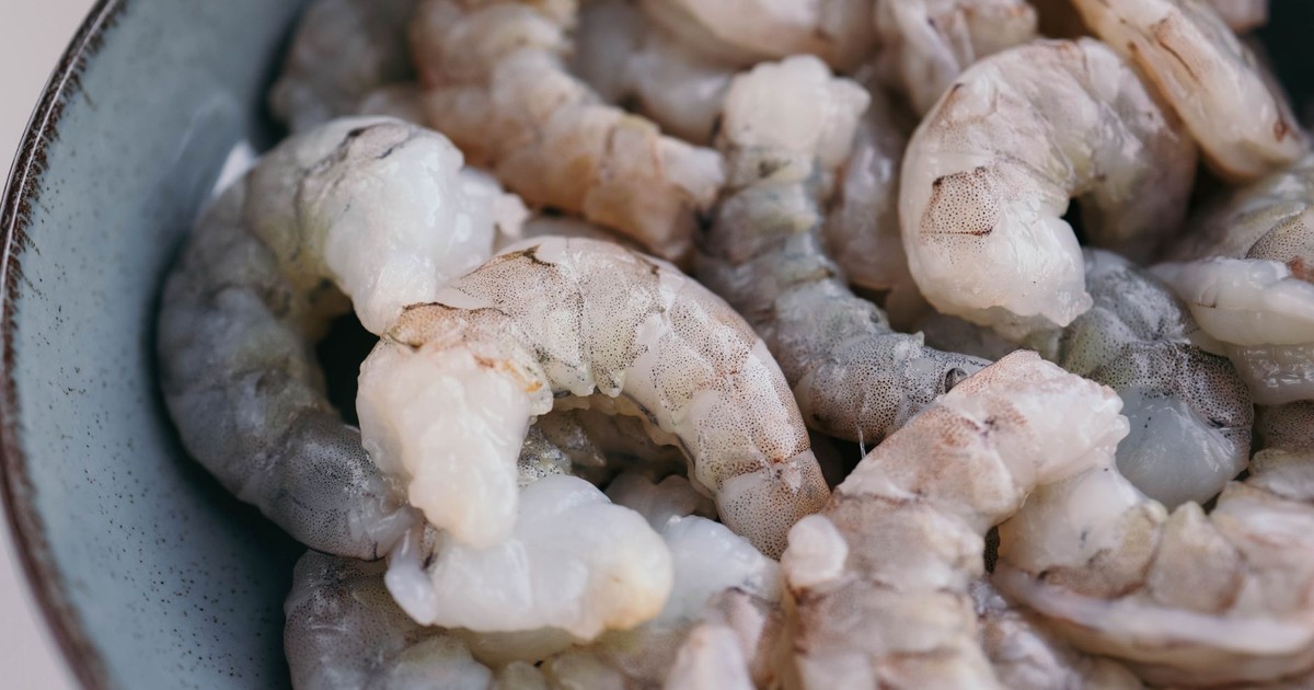 High-quality close-up of raw shrimps in a blue bowl, perfect for seafood-themed culinary projects.