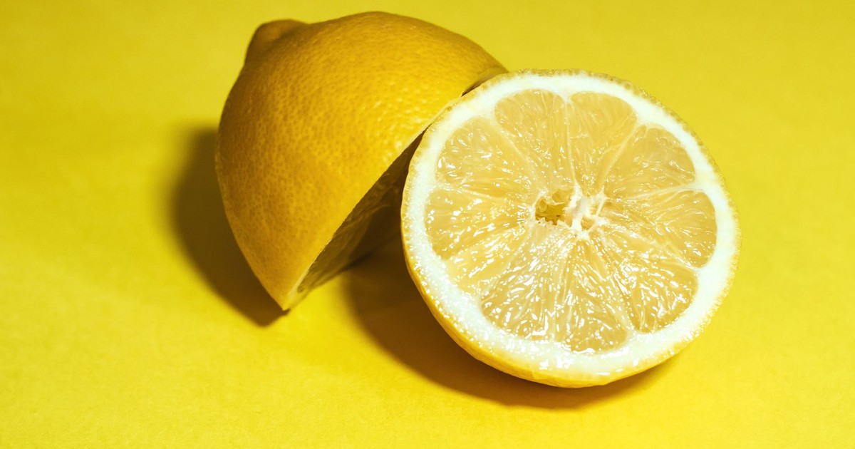 Close-up of a juicy lemon sliced in half, set against a vivid yellow background.