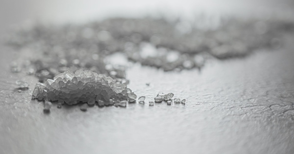 Detailed shot of coarse rock salt scattered on a textured surface.