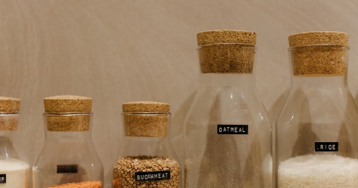 Close-up of various grains in labeled glass jars for kitchen storage.