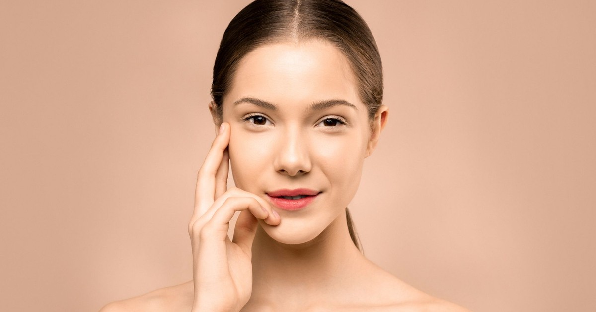 A close-up portrait of a young woman with flawless, radiant skin and a gentle smile, exuding natural beauty.