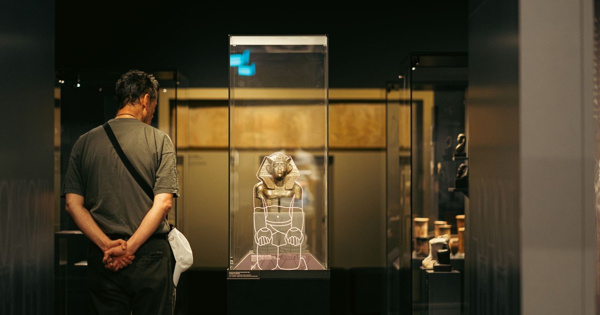 Visitor observing an ancient Egyptian artifact display in a Budapest museum exhibit.