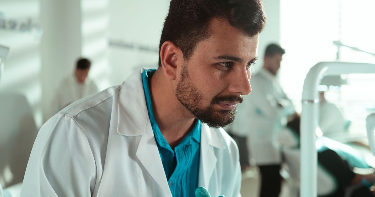 Middle Eastern male dentist focuses on patient care in a Baghdad clinic setting.