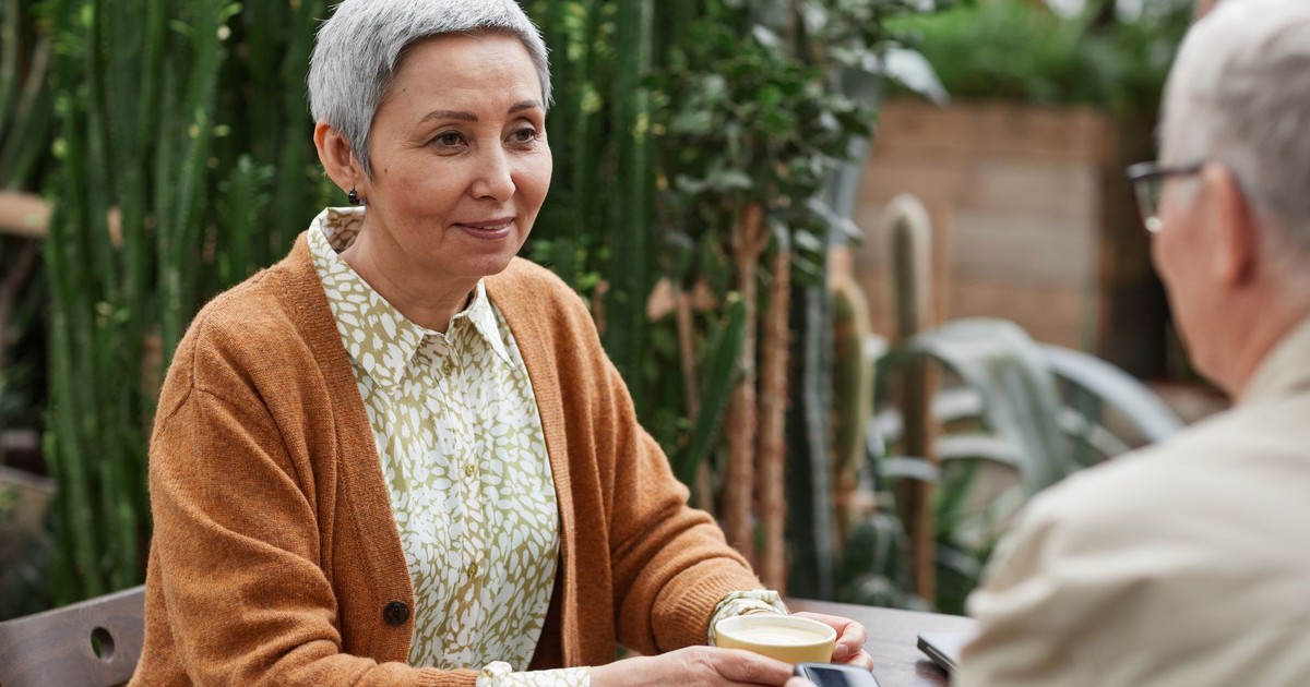 A senior couple enjoying coffee and conversation in a lush garden setting