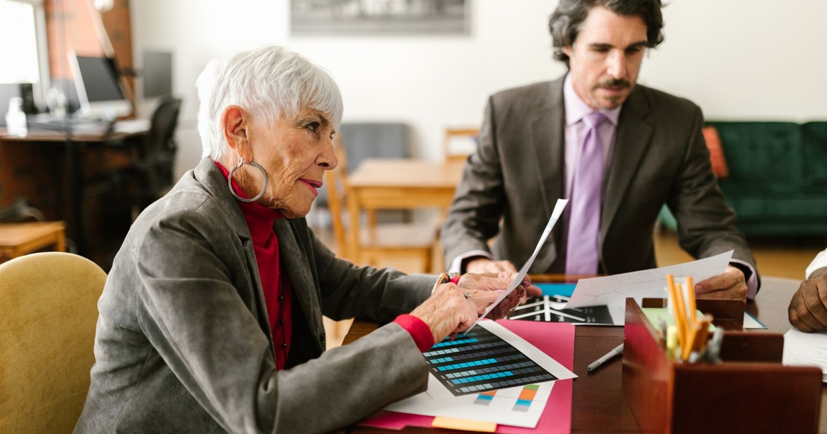 Colleagues discussing documents at a work desk in an office environment.