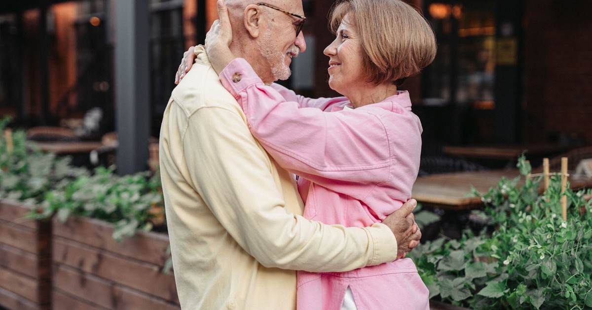 Elderly couple lovingly embracing outdoors, showcasing happiness and togetherness.