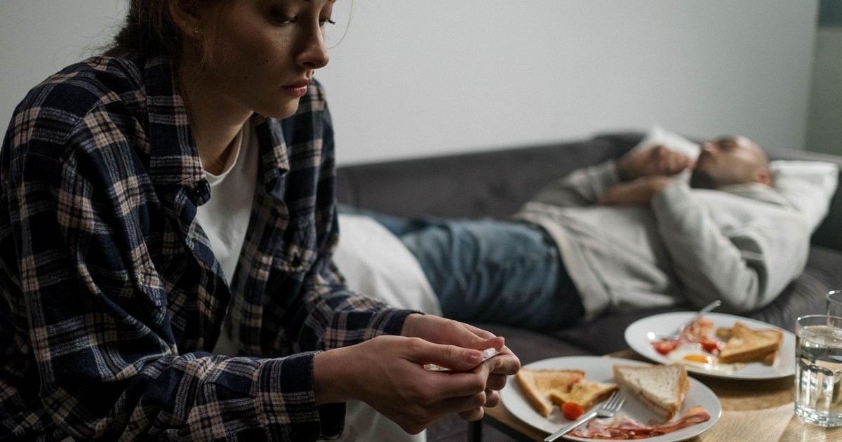 A couple in an intimate home setting reflecting on life's challenges, symbolized by untended breakfast.