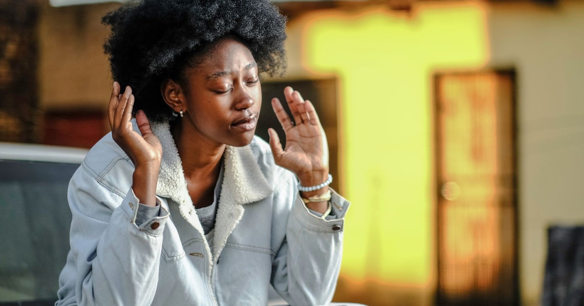 Portrait of a young African woman meditating on a car hood in Orange Farm, South Africa.