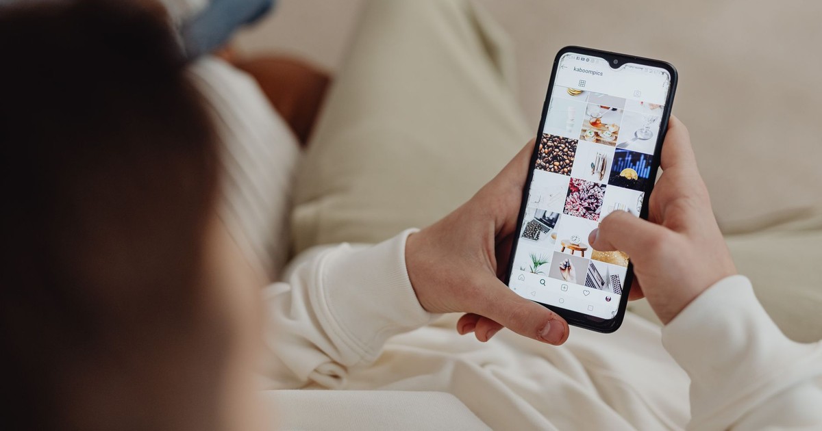 Person using smartphone to browse Instagram indoors, showing social media engagement.