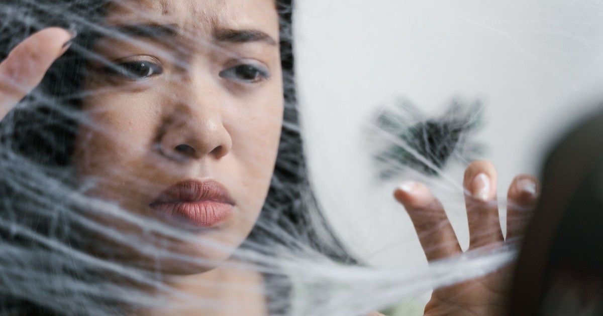 Close-up of a woman showing fear and anxiety as if trapped in a spider web.