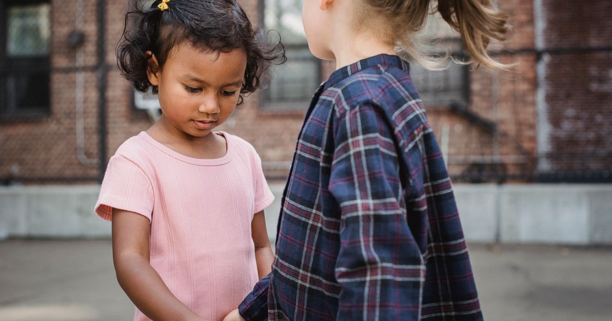 Two young girls holding hands outdoors, fostering friendship and connection.
