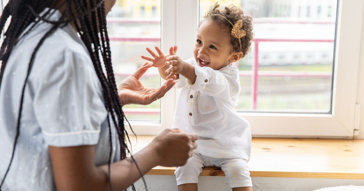 A joyful mother and baby bonding while playing on a sunny windowsill.