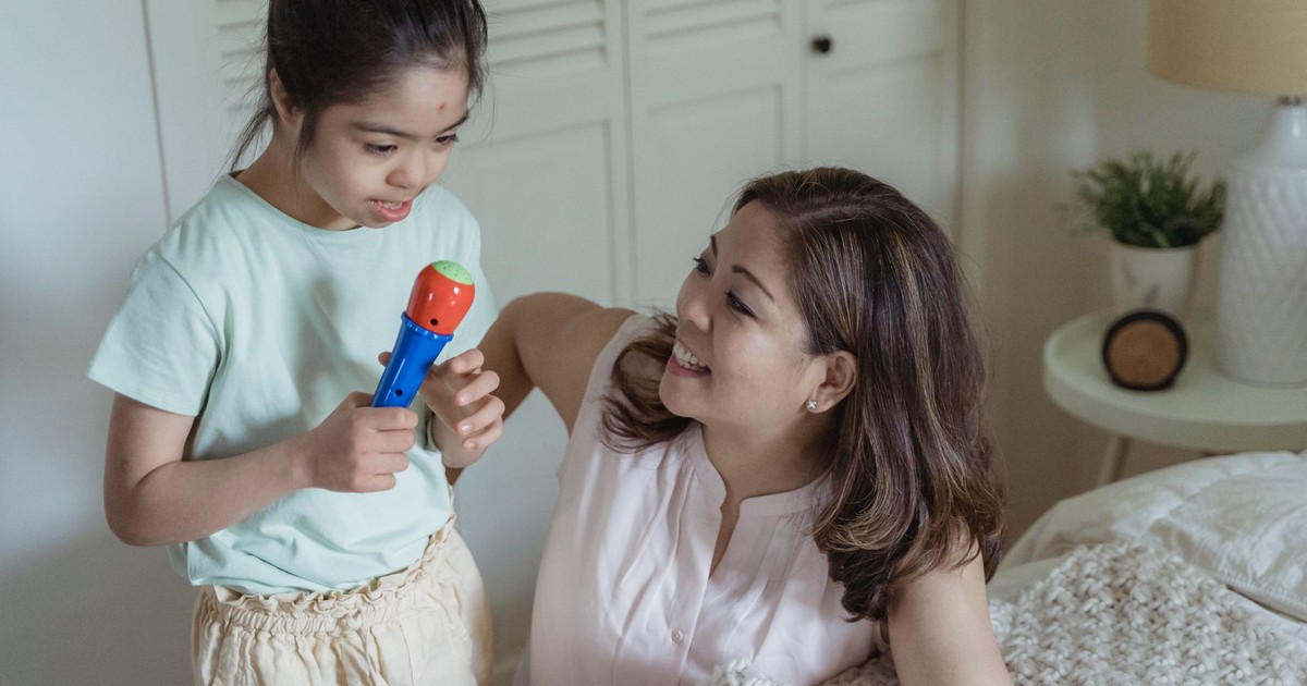 A happy mother engaging with her daughter holding a toy microphone, showing their strong bond.
