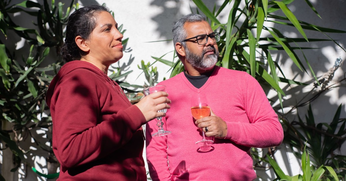Middle-aged couple sipping wine outdoors in Portugal, surrounded by greenery.