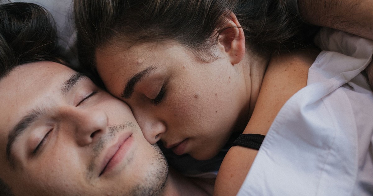 A close-up of an intimate couple cuddling and resting together in bed.