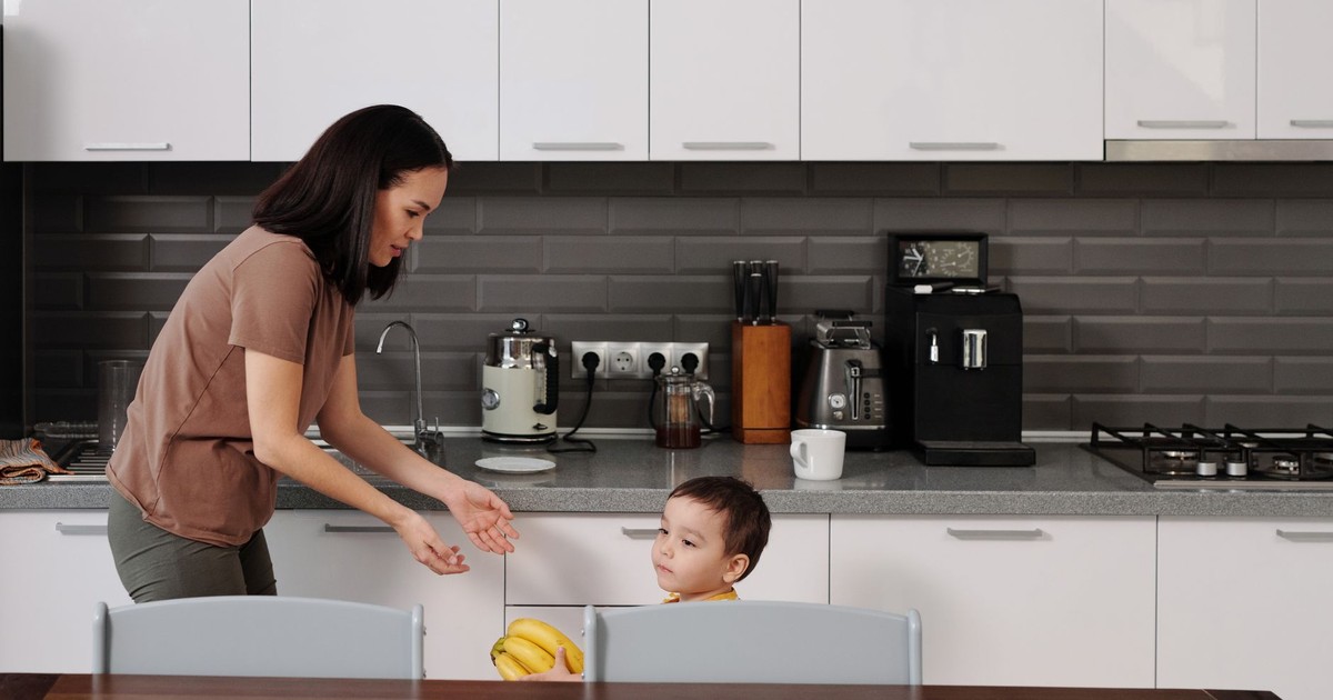 A mother and son engage in conversation in a contemporary kitchen setting.