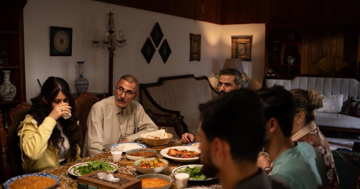 A family enjoys a traditional meal around a dining table in a warmly lit living room.