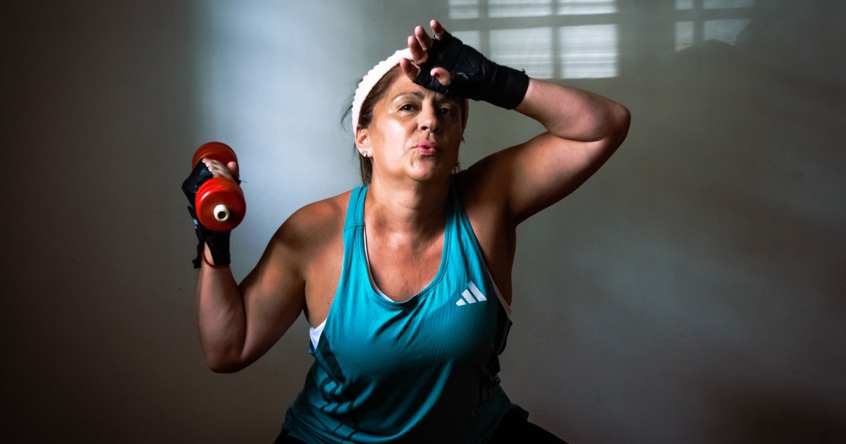 A determined woman working out at home with a dumbbell in focused exercise. Indoors motivational fitness.