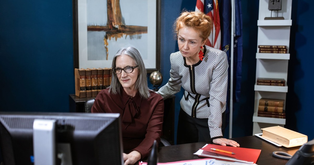 Two professional women collaborating at a desk in a modern office setting.