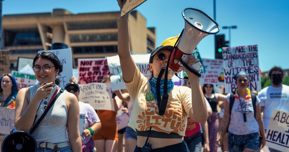 Diverse group of women advocating for rights during a peaceful protest, holding signs and megaphones.