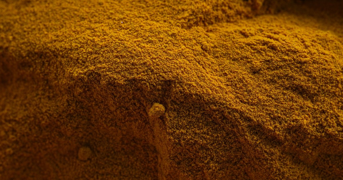 Close-up of vibrant yellow turmeric powder showcasing texture and color, ideal for food and culinary themes.