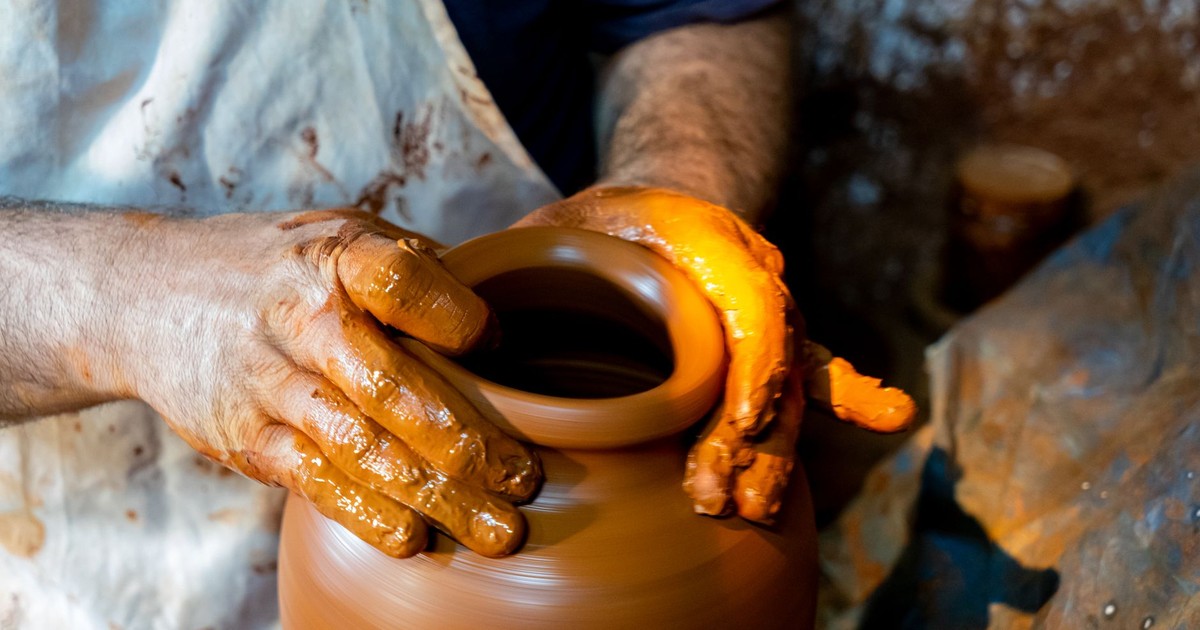 Close-up of hands shaping clay on a potter's wheel, demonstrating traditional craftsmanship.