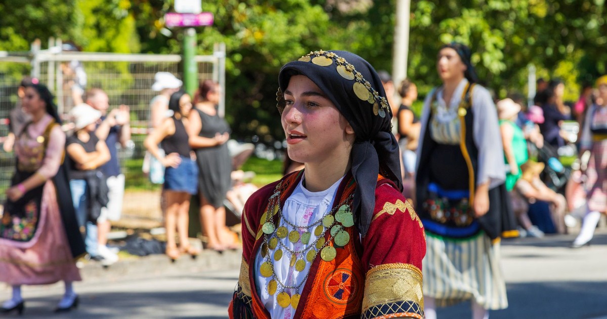 Woman wearing Greek traditional clothing participates in a vibrant outdoor parade.