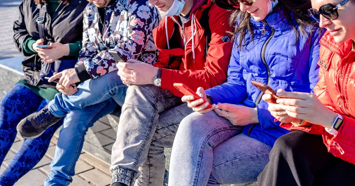 Casual group on city street using smartphones on a sunny day.