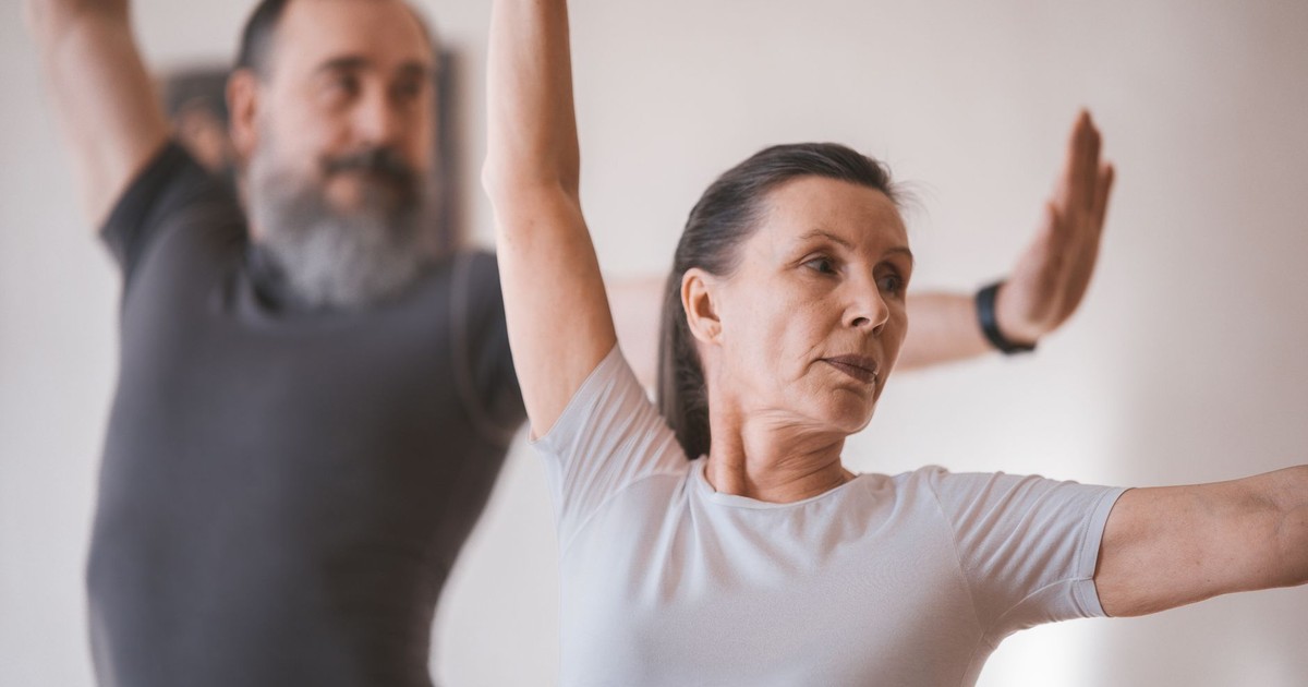 Senior adults in a yoga session indoors, focusing on stretching and balance.