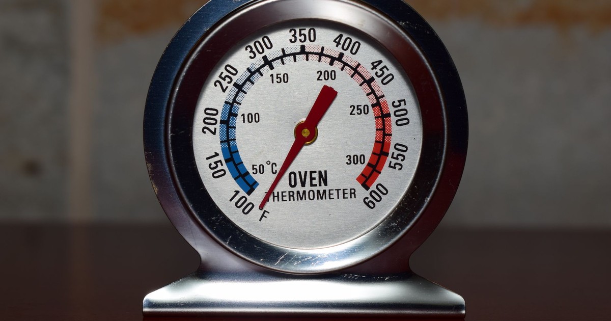 Close-up of a metallic oven thermometer showing temperature in Celsius and Fahrenheit.