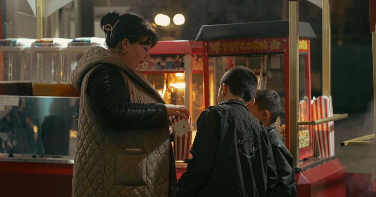 A woman and children buying popcorn at a night market stand in Uzbekistan.