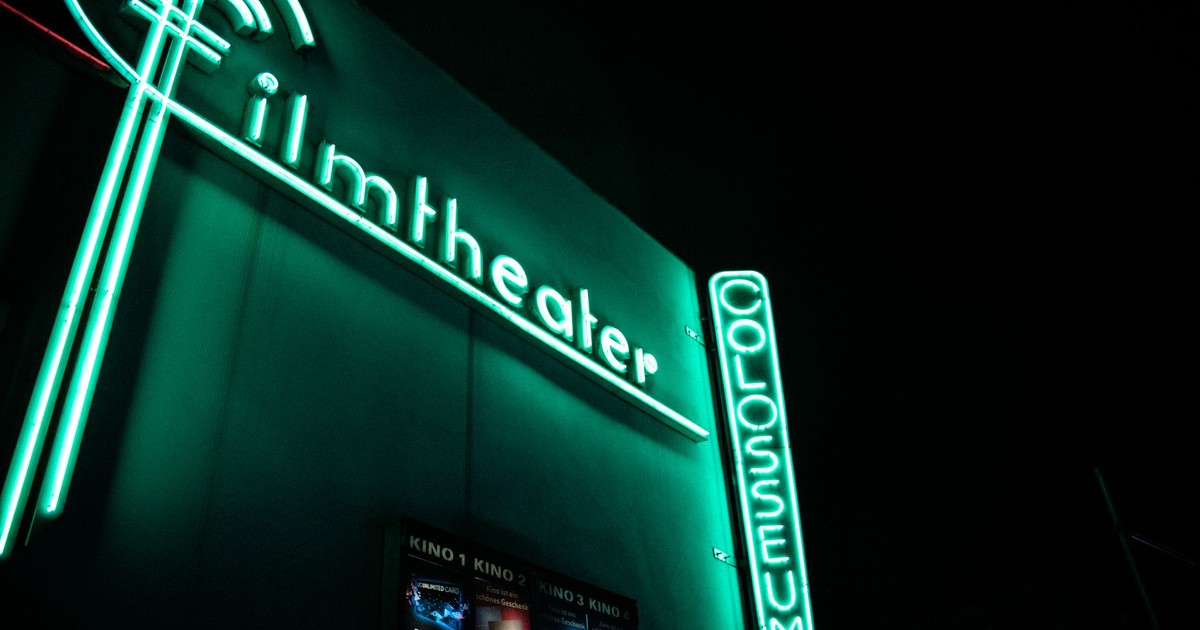 Vibrant neon film theater sign glowing at nighttime.