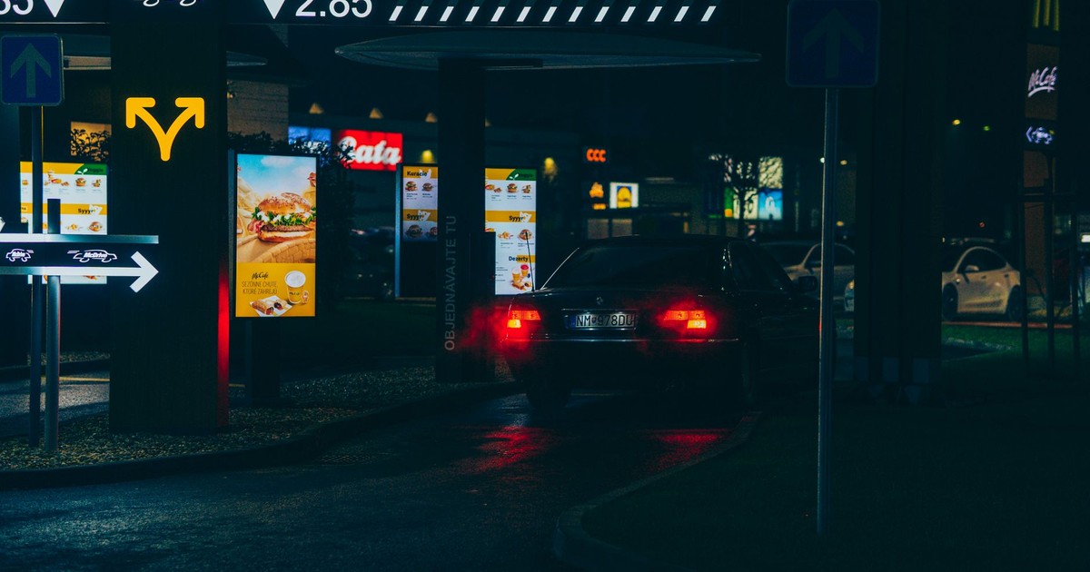 Car navigating a McDonald's drive-thru at night, showcasing urban dining atmosphere.