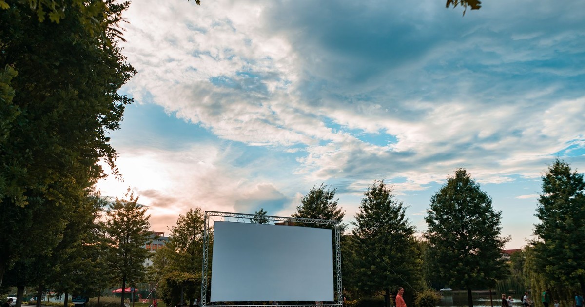 Experience the charm of an open-air cinema surrounded by lush greenery and a beautiful sunset.